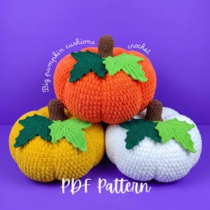 May include: Three crocheted pumpkin cushions in orange, yellow, and white, each featuring a brown stem and two green leaves. The text "Big pumpkin cushions crochet" and "PDF Pattern" is visible on the image against a solid purple background.