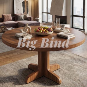 May include: A round wooden dining table with a central pedestal base and a cross-shaped foot. The tabletop features a bowl of assorted fresh fruit, stacks of books, a decorative sculpture, and the text Big Bind printed across the center.