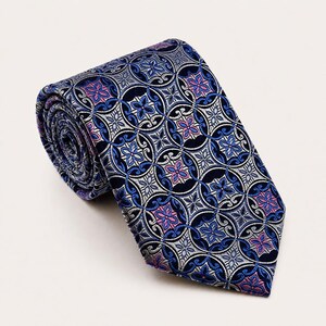 Könnte beinhalten: Eine Krawatte mit einem sich wiederholenden geometrischen Muster aus ineinandergreifenden Kreisen in Marineblau, Silber und Schwarz. Das Design enthält kleine, zentrierte blumenartige Motive in leuchtendem Pink und Blau für eine detaillierte Optik.