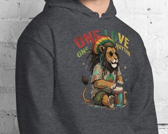 May include: A dark heather gray hooded sweatshirt featuring a graphic of a lion wearing a rasta-colored beanie and playing a drum. The text above the lion reads ONE LOVE and ONE RHYTHM in red, yellow, and green lettering. The hoodie has long sleeves.
