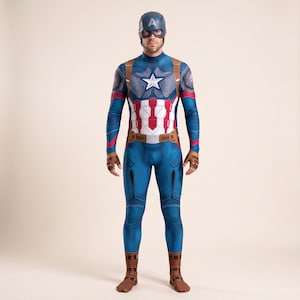 Op de afbeelding: Een volledig Captain America-kostuum bestaande uit een blauwe, rode en witte jumpsuit met een geprinte ster op de borst, bruine riem- en handschoendetails en een bijpassende blauwe hoofdbedekking met een A-embleem op het voorhoofd.