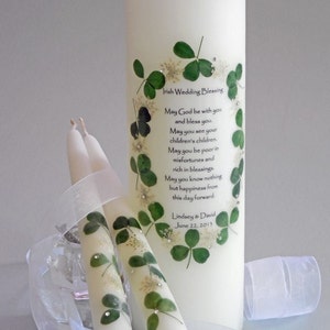 May include: Two white wedding unity candles decorated with green shamrocks and a white ribbon. The larger candle has the text "Irish Wedding Blessing" and a poem about happiness and blessings. The text at the bottom of the candle reads "Lindsey & David June 22, 2013".