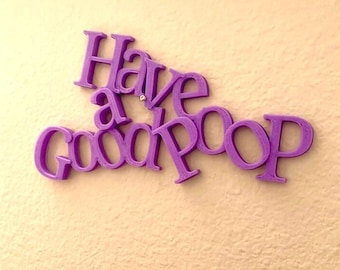 May include: Purple 3D letters spelling out "Have a good poop" on a light pink wall.