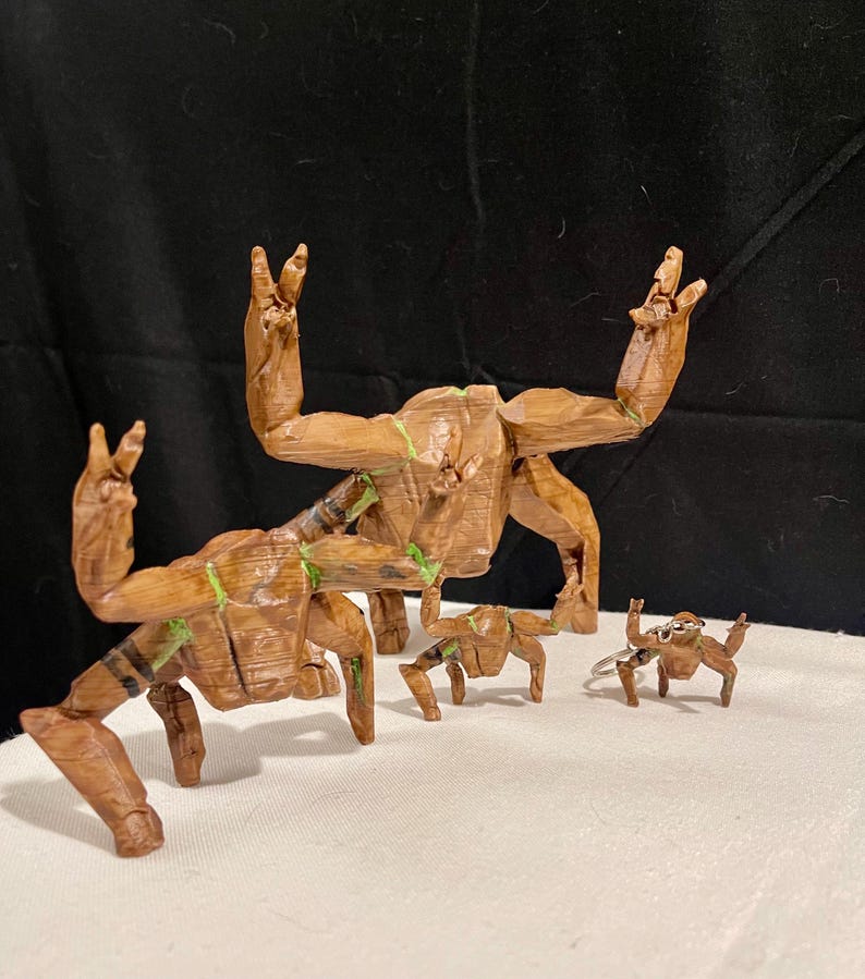 May include: A set of wooden Groot figures in different sizes. The figures are brown with green detailing and are posed with their arms raised in a peace sign. They are on a white surface with a black backdrop.