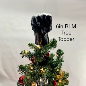 May include: A 6-inch black raised fist tree topper. The fist is made of a textured material and is a popular symbol of the Black Lives Matter movement.
