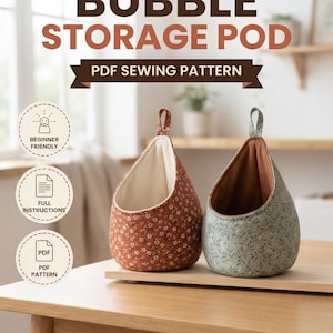 May include: Two fabric bubble storage pods with hanging loops. One pod is rust-colored with a white floral print and cream lining; the other is sage green with a dark leaf print and brown lining. Text includes ThreadAndNook, BUBBLE STORAGE POD, PDF SEWING PATTERN, BEGINNER FRIENDLY, FULL INSTRUCTIONS, PDF PATTERN, and INSTANT DIGITAL DOWNLOAD.