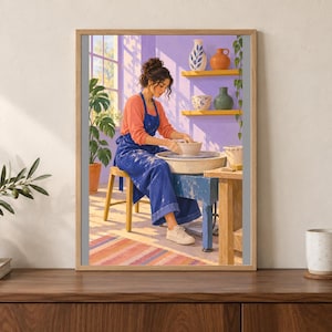 May include: A framed art print depicting a person in a coral long-sleeve shirt and blue apron working at a pottery wheel. The scene features a purple wall, yellow shelves with ceramic vases, a potted plant, and a window with sunlight.