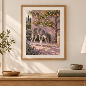 Puede incluir: Una lámina de arte enmarcada que muestra a un galgo de pie en un camino de grava bajo un árbol frutal. La escena incluye una pared rosa, plantas de lavanda y una fruta naranja caída en el suelo. La obra está en un marco de madera clara.