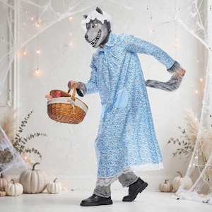 Puede incluir: Un disfraz de cuerpo completo que incluye una máscara de lobo gris con un gorro de encaje blanco, un camisón de manga larga con estampado floral azul, bolsillos azul claro y dobladillo de encaje blanco, pantalones grises, zapatos negros y cesta.