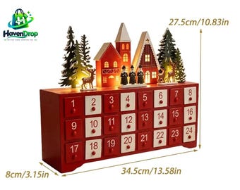 Puede incluir: Un calendario de adviento de madera con 24 cajones numerados del 1 al 24 en colores rojo y blanco. La parte superior muestra un pueblo festivo con casas iluminadas, árboles de hoja perenne y figuras. Mide 34,5 cm de ancho, 27,5 cm de alto y 8 cm de profundidad.