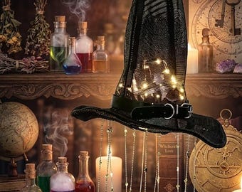 Puede incluir: Un sombrero de bruja negro de tela de malla texturizada, con una banda negra con hebilla plateada y luces de cadena de color blanco cálido en su interior. Varias cadenas finas colgantes con dijes de estrellas y lunas cuelgan del ala.