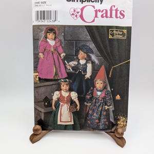 May include: Simplicity Crafts pattern 8500 featuring four dolls dressed in historical-style costumes. The cover displays dolls in a pink gown, a blue vest and hat, a green apron dress, and a floral dress with a tall pointed hat by Andrea Schewe.