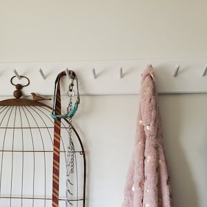 Modern coat rack 48 inches long with 11 pegs, ready to hang. Included 2 screw covers, 2 screws, and 2 drywall anchors, brief directions