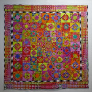 May include: A colorful quilt with a geometric pattern of squares and diamonds. The quilt is made with a variety of fabrics in shades of pink, red, yellow, green, and blue. The quilt is bordered with a black and white striped fabric.