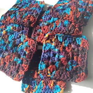 May include: A stack of crocheted fabric squares in shades of teal, purple, brown, and orange.