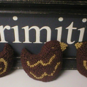 May include: Three brown, textured bird-shaped ornaments with tan accents. The birds are arranged in front of a black sign that reads "Primitives" in white letters. The ornaments have a rustic, handcrafted appearance.