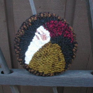 May include: A round wool rug with a design of a face with a red, white, and black background.