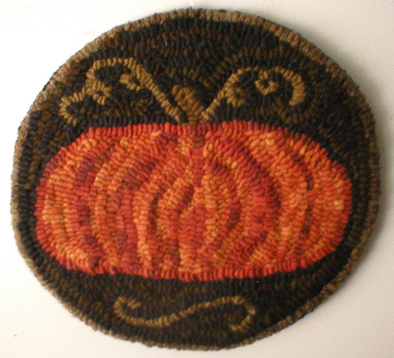 May include: A round, orange pumpkin rug with a brown and black border. The border has a swirling design.