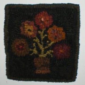 May include: A hand-stitched rug with a dark brown background featuring a vase with five colourful flowers in shades of orange, red, and yellow.