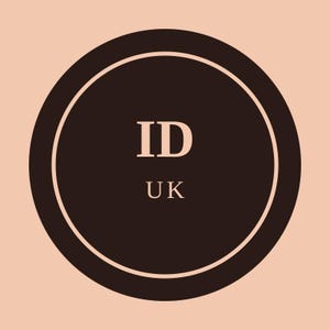 Op de afbeelding: Een cirkelvormig grafisch ontwerp met een donkerbruin midden, omsloten door een dunne lichtperzik kleurige rand. De tekst ID staat boven de tekst UK, beide in een lichte perzikkleur, gecentreerd in het donkerbruine cirkelvormige veld.