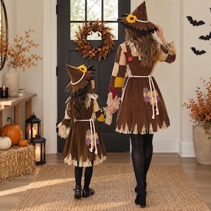 May include: Two matching scarecrow costumes featuring brown corduroy dresses with colorful fabric patches, frayed hemlines, and white rope belts. Each costume includes a pointed brown hat adorned with a yellow sunflower and black trim.