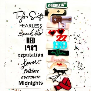 May include: A white card with the text "Taylor Swift" and the names of her albums: "Fearless", "Speak Now", "Red", "1989", "reputation", "Lover", "folklore", "evermore", and "Midnights".  The card is decorated with colorful stickers representing each album.