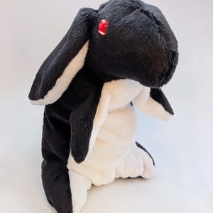 May include: A plush toy rabbit in black and white, with long ears and red eyes. The stuffed animal has a soft, fluffy texture and is designed to resemble a rabbit. The toy is suitable for children and makes a great gift.