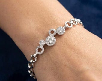 May include: A silver-toned chain bracelet featuring a series of circular links, with three central circular stations encrusted with small clear stones. The bracelet has a polished metallic finish and a secure link construction.