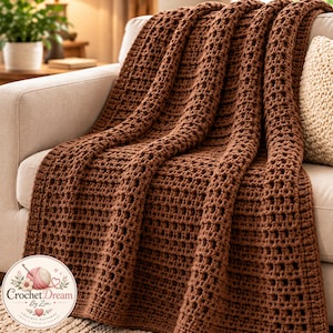 Puede incluir: Una manta de ganchillo de color marrón sólido con un patrón de rejilla texturizado y repetitivo drapeada sobre un sofá. En la esquina inferior izquierda, un logotipo circular muestra un ovillo de lana, flores y el texto Crochet Dream By Zin, Crochet Patterns.