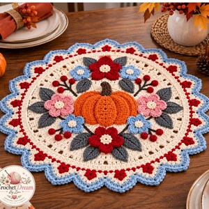 May include: A round crochet doily featuring a central orange pumpkin surrounded by red, pink, and light blue flowers with dark gray leaves. The cream-colored base has a scalloped border in red and light blue. A logo with the text Crochet Dream By Zin.
