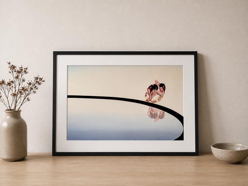 Op de afbeelding: Een ingelijste horizontale kunstdruk met een surrealistische illustratie van twee figuren die gehurkt op een gebogen zwarte lijn zitten tegen een verloopachtergrond. De figuren worden weerspiegeld in een blauw gebied onder de lijn.