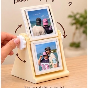 May include: A cream-colored rotating photo frame with two square slots for pictures. The frame features white side knobs for manual rotation. Text on the image reads: Rotate • Display • Smile and Easily rotate to switch between your favourite photos.
