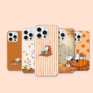 Peut inclure: Cinq coques de smartphone avec des motifs automnaux de Snoopy et Woodstock. Les coques présentent des tons orange, crème et marron avec des illustrations de citrouilles, de feuilles mortes et les personnages lisant ou ratissant, avec le texte RAKE.