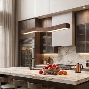 May include: A linear wooden pendant light fixture with a zig-zag shape suspended over a kitchen island. The fixture features a dark wood grain finish and a downward-facing light panel that illuminates the marble countertop and fruit bowl.
