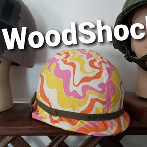 May include: A colourful helmet with a pink, orange and yellow swirl pattern. The helmet has a green strap with the word "PHILLY" printed on it. The helmet is sitting on a wooden surface.