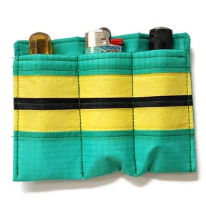 May include: A teal and yellow pouch with three pockets, each holding a different item. The first pocket contains a clear, cylindrical object. The second pocket holds a lighter and a small box. The third pocket holds a black, cylindrical object.