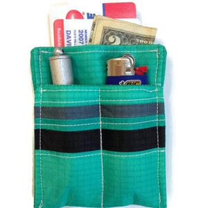 May include: A small, teal-colored pouch with black and gray stripes. The pouch has two pockets, one containing a silver lighter and the other containing a lighter.