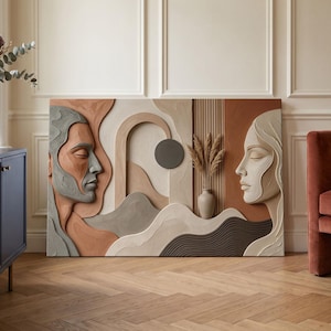 Puede incluir: Una pieza de arte mural rectangular con un diseño en relieve texturizado y en capas. Muestra dos rostros de perfil en tonos gris, beige y terracota, separados por una sección central con un elemento circular, listones verticales y un jarrón.