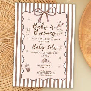 May include: A rectangular baby shower invitation card with a brown and white vertical striped border. The center features a light pink scalloped frame with a brown bow, coffee-themed illustrations, and text reading Baby is Brewing.