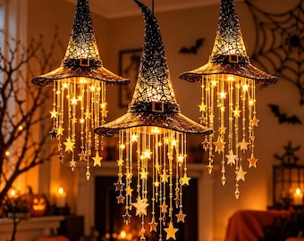 May include: Three black witch hat pendant lights featuring a textured, lace-like fabric finish and a decorative buckle. Each hat is illuminated from within and adorned with cascading strings of glowing star-shaped ornaments and clear crystals.