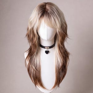 May include: A long, layered wig featuring a blend of platinum blonde and light brown tones with a curtain fringe. The hair is styled in a shaggy, voluminous cut that falls past the shoulders. A black choker with a heart-shaped pendant is worn.