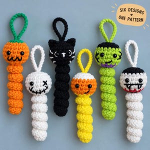 Puede incluir: Seis adornos colgantes de ganchillo con personajes de Halloween, incluyendo una calabaza, un fantasma, un gato negro, un caramelo, un monstruo y un vampiro. Cada adorno tiene un lazo y un cuerpo en espiral. Texto: SIX DESIGNS ONE PATTERN.