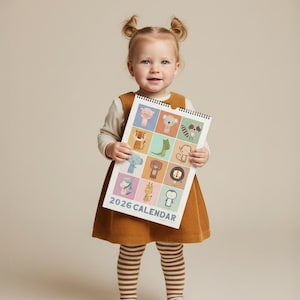 May include: A child holds a 2026 calendar featuring colorful animal illustrations. The calendar measures 11" x 16.5" and has a spiral binding. The child is wearing a brown corduroy dress, a white long-sleeve shirt, and striped socks.
