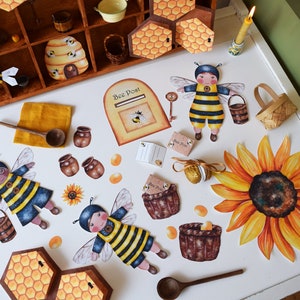 May include: A charming assortment of bee-themed paper cutouts and decorative items. Features bee characters, a sunflower, honey pots, a wooden spoon, and a miniature beehive. The color scheme includes yellow, brown, and blue, creating a delightful, handcrafted aesthetic.