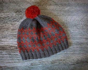 May include: A gray knitted beanie with a red pom pom and a geometric pattern.