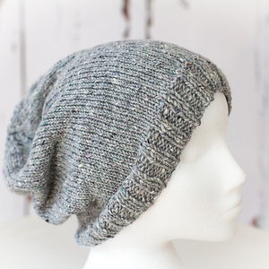 May include: A gray slouchy beanie with a subtle flecked pattern. The beanie is knit and has a folded brim.