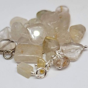 May include: A pile of clear quartz crystals with a silver chain and clasps. The crystals are various shapes and sizes.