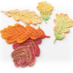Puede incluir: Cuatro hojas de roble de ganchillo en tonos naranja, amarillo y verde. Las hojas est&aacute;n hechas con un delicado patr&oacute;n de puntadas y tienen una superficie ligeramente texturizada.