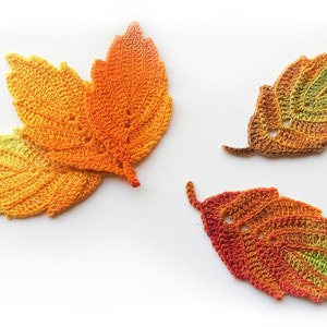 Puede incluir: Tres hojas de ganchillo en tonos de naranja, amarillo y verde. Las hojas est&aacute;n hechas con un hilo fino y tienen una textura delicada y de encaje.