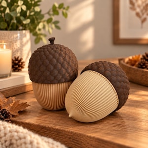May include: Two decorative acorn-shaped objects featuring dark brown textured caps with a realistic scale pattern and smooth, light beige ribbed bases. One acorn stands upright while the other rests on its side, showcasing the vertical ridged detail.
